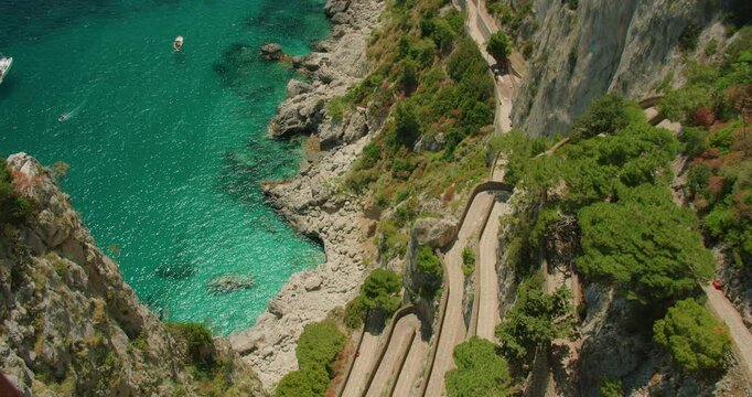 Scenic view of Via Krupp winding above turquoise sea as summer boats anchor in Marina Piccola Capri Italy