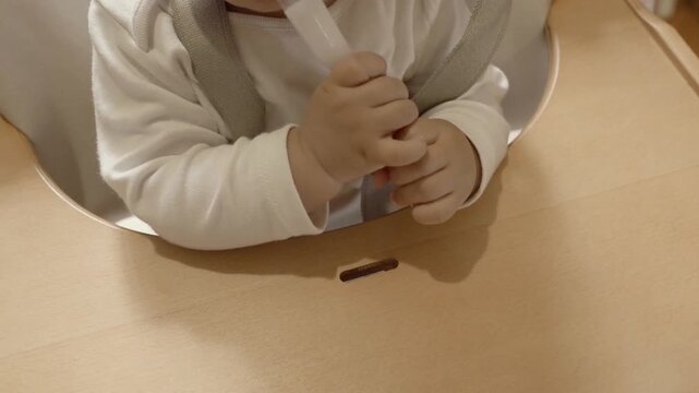 Curious baby learning to hold a spoon