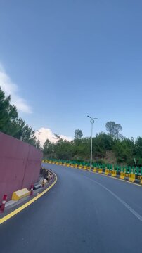 A smooth vertical driving video captured on the scenic Murree Expressway in Pakistan. Featuring a winding mountain road, lush green pine forests, modern streetlights, and a peaceful travel atmosphere.
