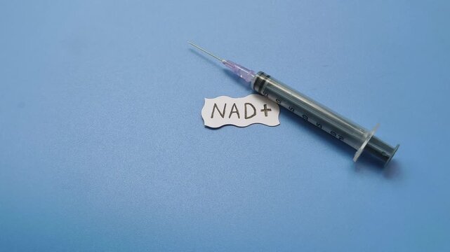 Syringe near NAD+ word. NAD plus medicine injection for cellular recovery, performance enhance, beauty treatment, cell repair, longevity, skin care, anti-aging, life extension and healing assistance.