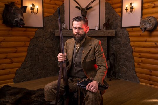Hunter in traditional tweed clothing sitting and holding his rifle vertically