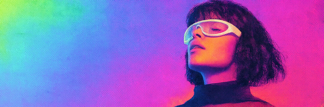 Young woman wearing futuristic glasses experiencing synesthesia against a vibrant rainbow neon gradient background