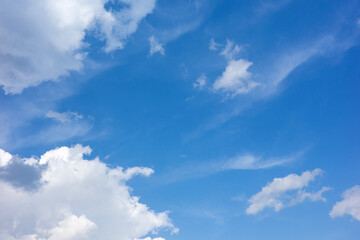 Obraz premium A vast, serene azure sky filled with scattered, light-filled white clouds stretches across the entirety of the atmospheric frame above.