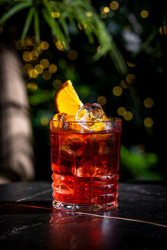 Negroni mocktail zero proof non alcoholic cocktail drink in elegant crystal glassware. Balanced vertical shot layout under targeted cinematic spotlight for luxury hospitality promotion.