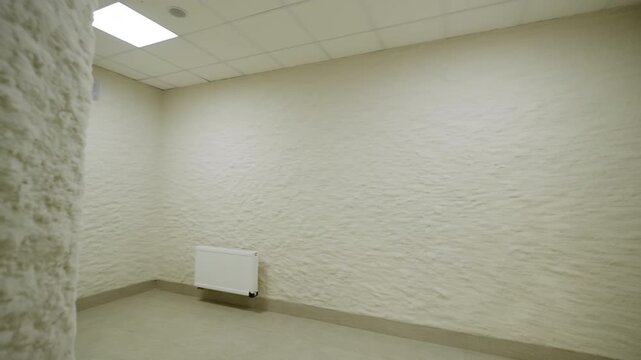 Modern healthcare facility shows halotherapy salt cave under bright ceiling lights. Pristine therapeutic space feels highly organized