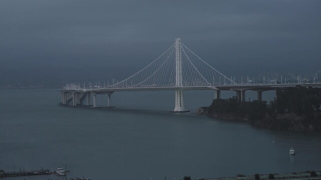 Cable-Stayed Bridge Over Bay Under Dark Overcast Sky At Dusk - Wide, Drone Shot