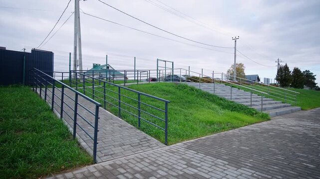 Spacious grey courtyard features comfortable pedestrian ramp on lawn background. Clean contemporary territory feels safe and fresh