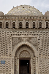 Fototapeta premium Ismail Samani Mausoleum facade in Bukhara Uzbekistan showing intricate geometric brickwork and dome. Ideal for travel publications, history articles, and architectural studies.