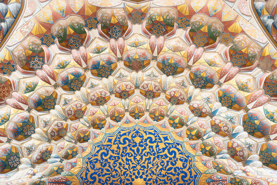 Ornate muqarnas ceiling of Abdulaziz Khan Madrasah in Bukhara featuring polychrome painted honeycomb vaulting with floral and geometric motifs. Ideal for architecture, heritage, design publication.
