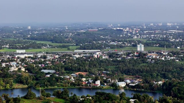 Cinematic aerial view of Aluva showcasing the elevated Kochi Metro station surrounded by dense tropical greenery, residential neighborhoods, and expanding urban development.