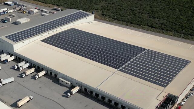 Large cold storage port warehouse with massive rooftop solar array and refrigerated trucks loading at multiple bays.