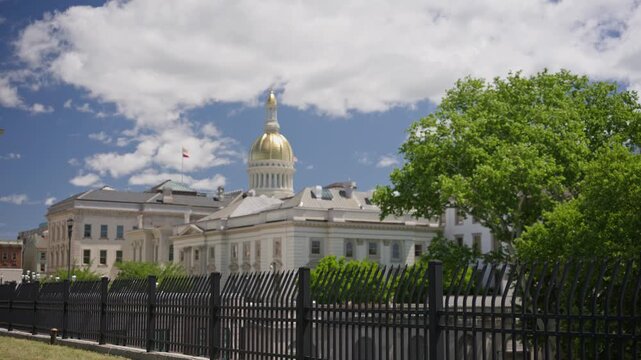 Cinematic movement along a historic fence line revealing the New Jersey State House capitol building in downtown Trenton New Jersey on a sunny day.