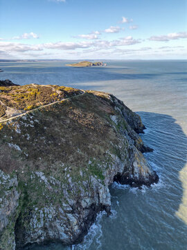 Aerial view of the rugged Howth cliffs with a coastal path, rocky terrain, and the island of Ireland's Eye in the distance, Dublin, County Dublin, Ireland.