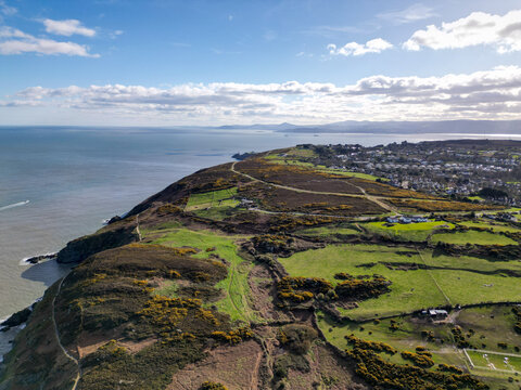 Aerial view of the Howth peninsula featuring rugged coastal cliffs, grassy hills, walking paths, and residential areas overlooking the Irish Sea in Dublin, County Dublin, Ireland.