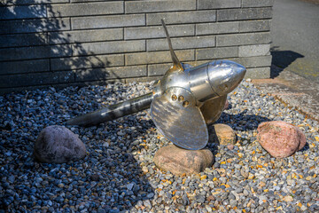Metal boat propeller displayed on stones as industrial maritime object. © Trygve