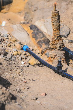 Exposed underground utility pipe crossing sandy trench during infrastructure repair.