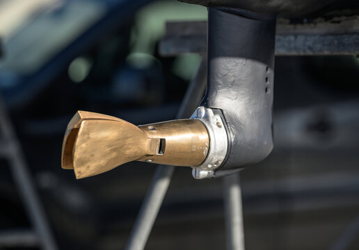 Brass boat propeller close up on dark stern drive.