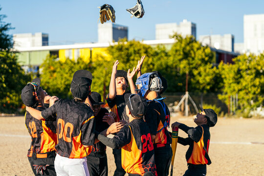 Young baseball players huddling and cheering after winning a game, showing camaraderie and achievement on the field