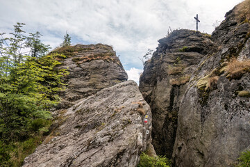 Fototapeta premium Summit cross on the Rauchröhren rock formation along Kaitersberg ridge in the Bavarian Forest, Germany.