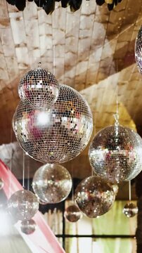 Vertical video. Wedding decor with hanging mirror disco balls inside outdoor reception tent.