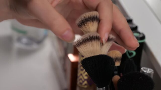 50p slow motion close up shot of a teenage girl selecting a makeup brush from a collection of cosmetic tools during her beauty routine