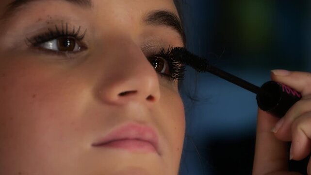 50p extreme close up shot of a teenage girl applying mascara to her eyelashes during a beauty routine, highlighting eye makeup and cosmetic application