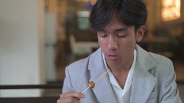 Portrait of young person from Southeast Asia Thai Isan region sitting and eating