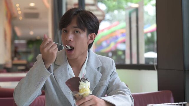 Portrait of smiling non-binary Thai Isan person eating sundae ice cream dessert during day