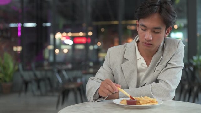 Smiling young nonbinary Thai business professional looking away with french fries at cafe horizontal shot