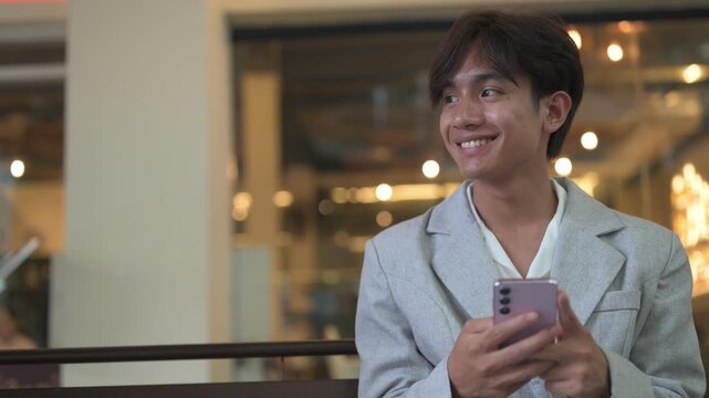 Portrait of smiling non-binary Thai Isan person using phone at night