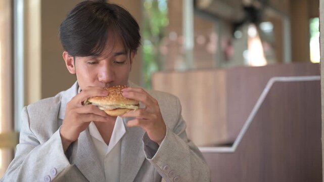 Portrait of young hungry person from Southeast Asia Thai Isan region eating delicious hamburger