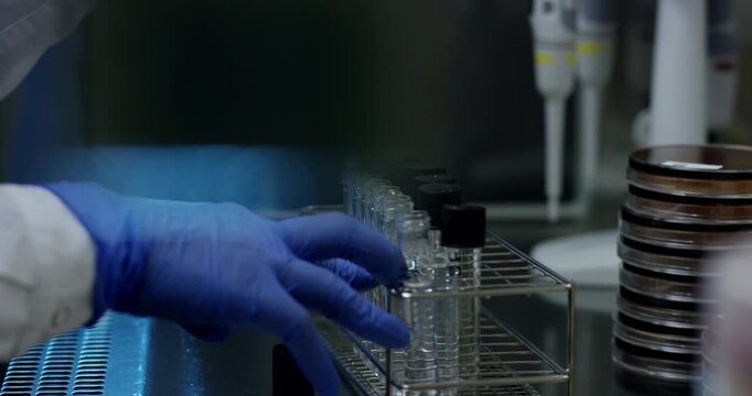 Scientist in blue gloves using a pipette to transfer liquid into a glass vial in a laboratory