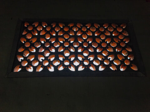 Close up of traditional terracotta roster block ventilation with floral pattern on a dark wall