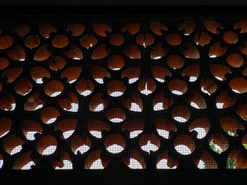 Close up of traditional terracotta roster block ventilation with floral pattern on a dark wall