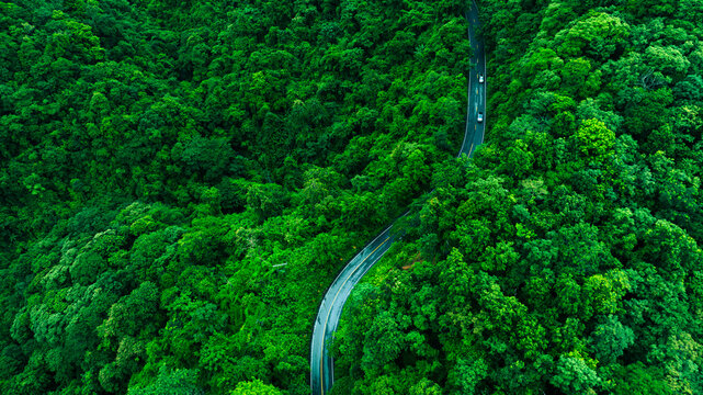 Aerial forest road with car creating abstract background for electric vehicle, ESG, sustainability and green investment business concepts.