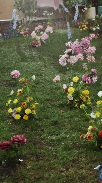 Vertical video. Rain falls on wedding floral decor placed on grass in a forest meadow.