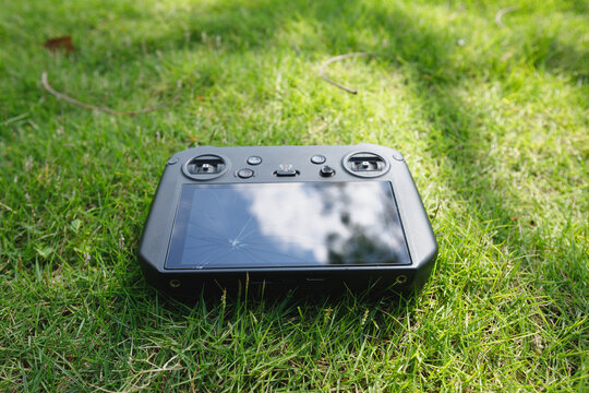 Broken drone remote controller on the green grass