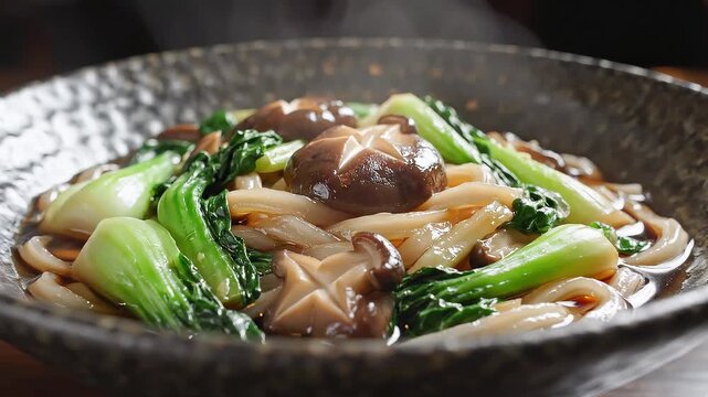 A close-up shot of a steaming bowl of stir-fried shiitake mushrooms, bok choy, and noodles in a savory sauce, presented in a dark ceramic bowl.