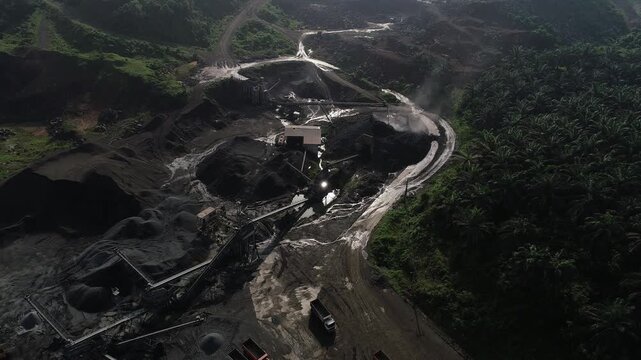 Aerial drone descent shot of heavy excavators and trucks operating at a large industrial mining and quarry site.