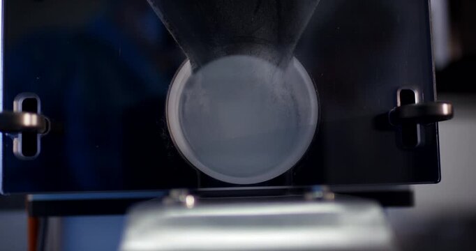 Top view of white medical capsules falling through clear tube during production process in manufacturing plant
