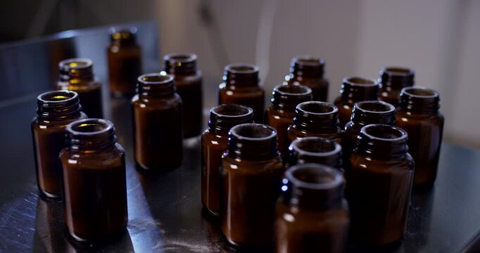 Row of empty brown glass bottles standing on stainless steel table in production plant facility