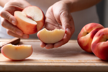 Woman hands holding a sliced fresh white peach, ready to eat