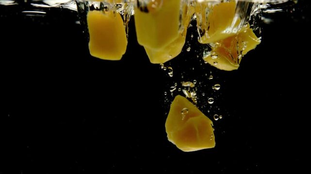 Super slow motion cinematic footage of fresh ripe mango and juicy pineapple plunging into crystal-clear water against a pure black background, filmed with a high-speed cinema .