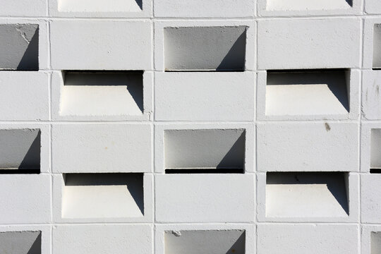 Full frame background texture of a white architectural breeze block wall casting sharp geometric shadows under bright daylight