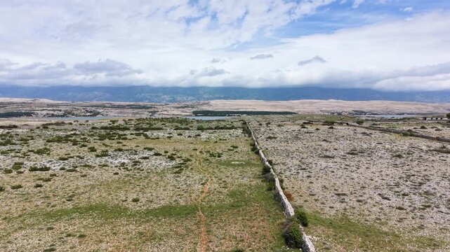 rone view of Pag Island stone walls, barren terrain and mainland coast in Croatia.