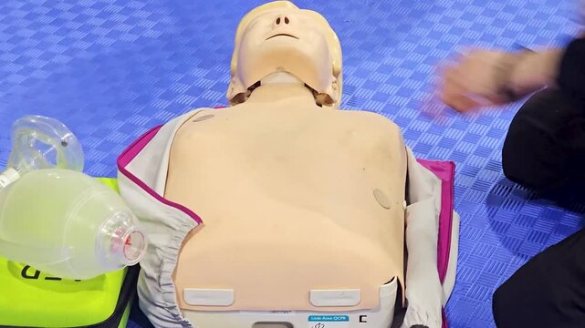 First Aid Training on Mannequin Showing CPR Chest Compression and Medical Equipment