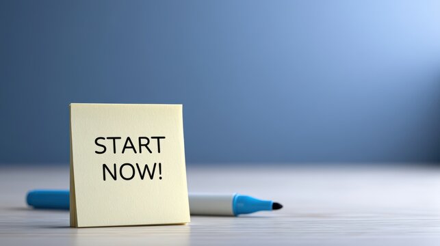Yellow sticky note with text Start Now on desk with marker