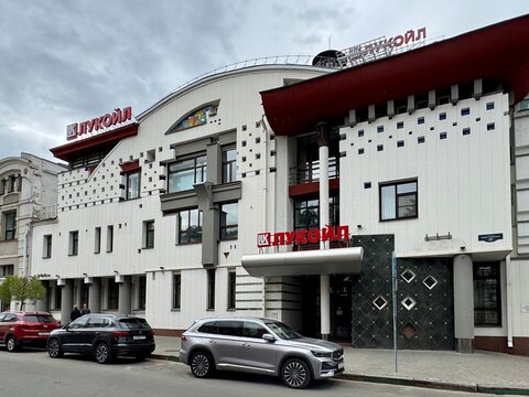 Russia Nizhny Novgorod 28 june 2026 lukoil building with parked cars on urban street scene at neutral level perspective showing concrete, glass, and metal materials in commercial real estate setting.