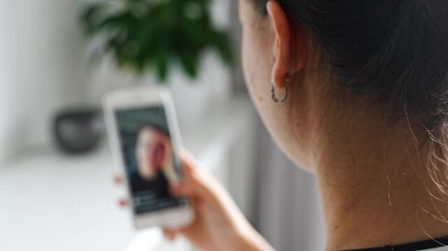 Woman scrolling social media on a smartphone at home. Digital addiction concept with endless content consumption and screen time.