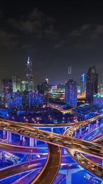 Vertical  panning night time lapse of busy elevated road intersection with commuters with neon lighting, at night, Asia, China, Shanghai